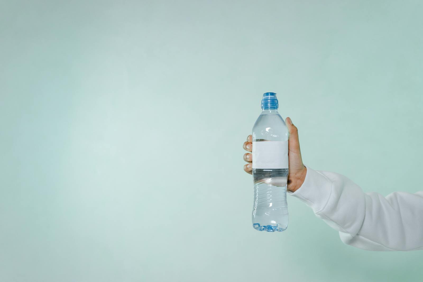 Photo of a Person's Hand Holding a Bottle of Water
